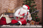 santa-claus-plays-guitar-background-christmas-tree-bag-gifts-31371818.jpg